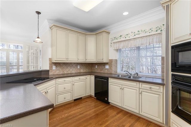 kitchen featuring ornamental molding, a sink, black appliances, cream cabinetry, and dark countertops