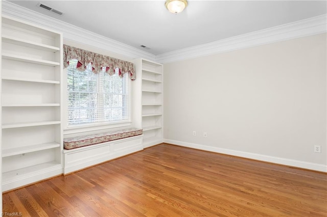 unfurnished room with visible vents, ornamental molding, built in features, wood finished floors, and baseboards