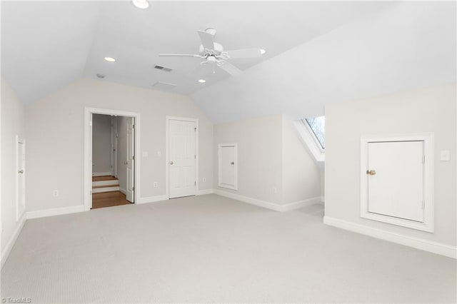 additional living space featuring lofted ceiling with skylight, light colored carpet, visible vents, and baseboards