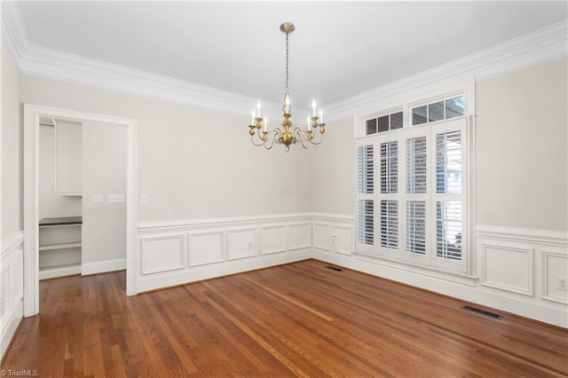 unfurnished dining area featuring visible vents, wood finished floors, a chandelier, and crown molding