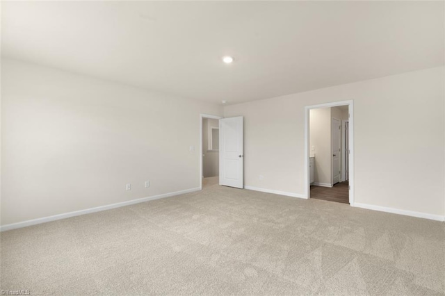 unfurnished bedroom featuring light colored carpet and ensuite bathroom