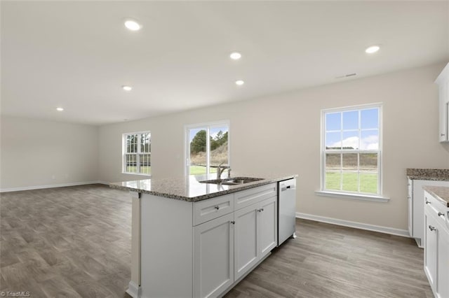 kitchen featuring a center island with sink, dishwasher, light wood-type flooring, and white cabinetry