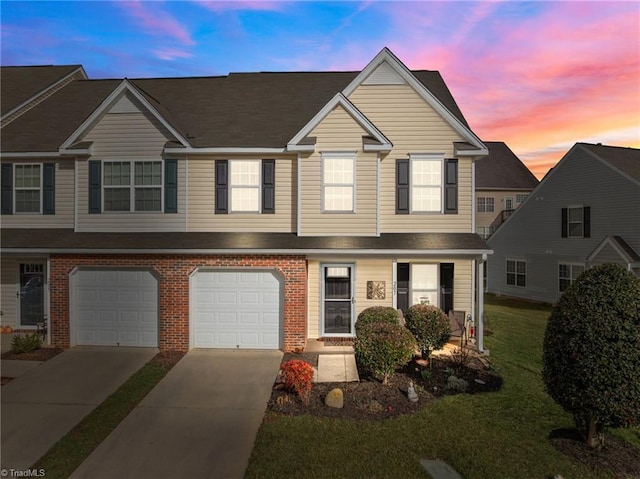 townhome / multi-family property with a garage, driveway, and brick siding