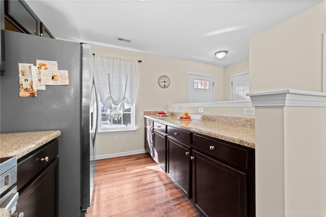 kitchen featuring light wood finished floors, baseboards, visible vents, stainless steel fridge with ice dispenser, and dark brown cabinets