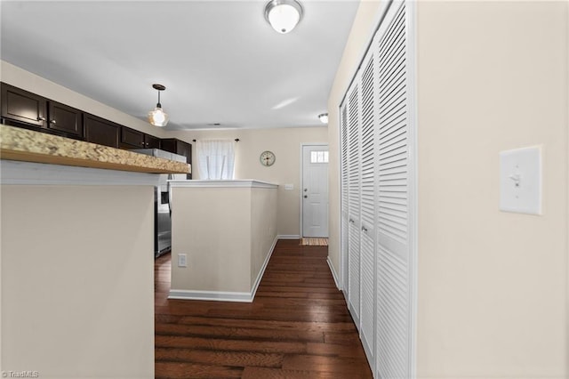 hall featuring dark wood-style flooring and baseboards