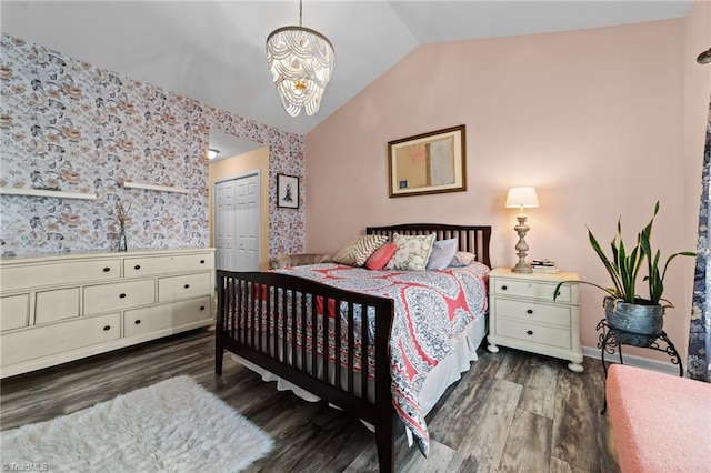 bedroom with lofted ceiling, wood finished floors, a closet, wallpapered walls, and an inviting chandelier