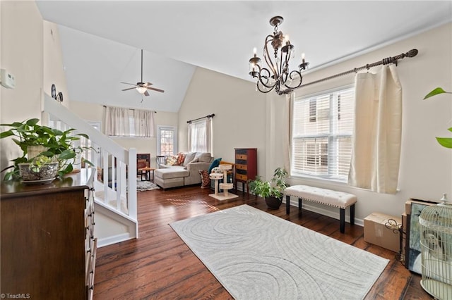 living area with dark wood-style floors, ceiling fan with notable chandelier, high vaulted ceiling, and stairs