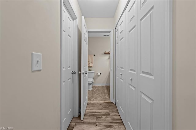 corridor with wood finished floors and baseboards