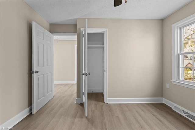 unfurnished bedroom with baseboards, visible vents, light wood finished floors, and multiple windows