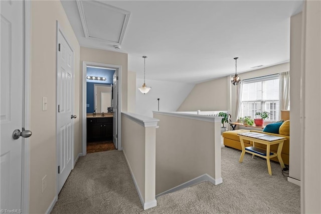 corridor with attic access, light carpet, vaulted ceiling, an upstairs landing, and baseboards