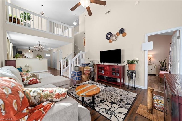 living area featuring baseboards, visible vents, stairway, wood finished floors, and ceiling fan with notable chandelier