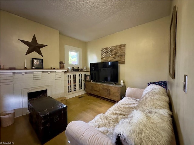 living room with a fireplace, a textured ceiling, and light wood-type flooring