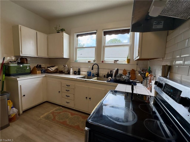 kitchen featuring sink, tasteful backsplash, ventilation hood, light hardwood / wood-style flooring, and stainless steel electric stove