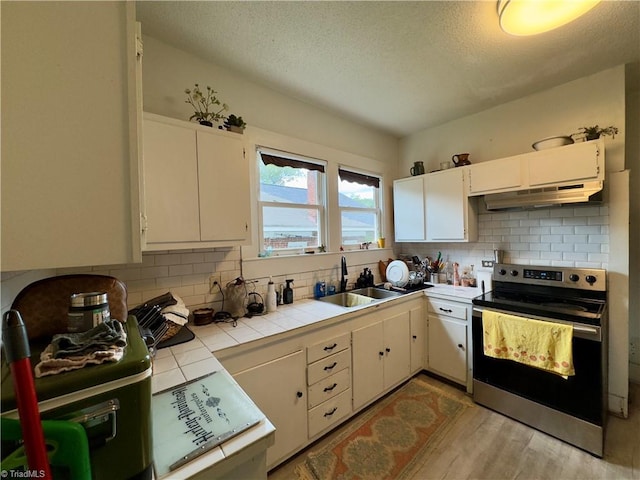 kitchen featuring white cabinetry, stainless steel electric stove, sink, and tile counters