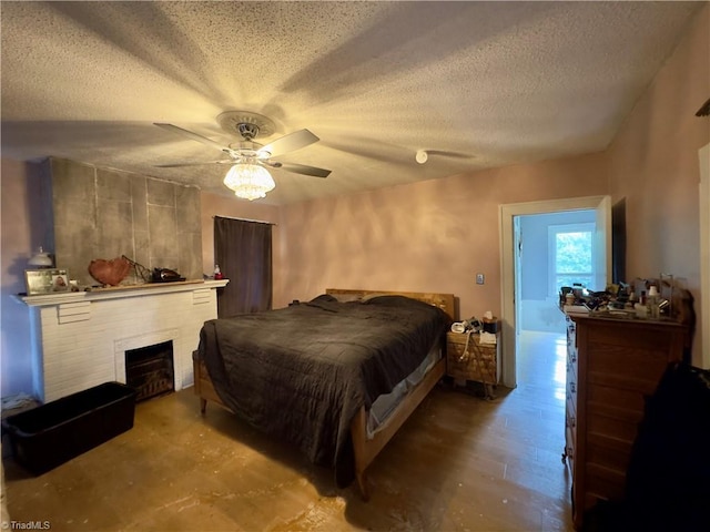 bedroom with ceiling fan, a fireplace, and a textured ceiling