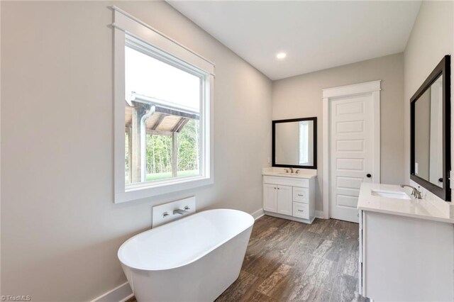 bathroom with vanity, a bath, and hardwood / wood-style flooring