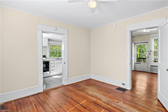 empty room featuring a wall unit AC, visible vents, ornamental molding, a sink, and hardwood / wood-style flooring