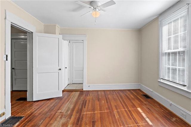 unfurnished bedroom with wood-type flooring, visible vents, crown molding, and baseboards