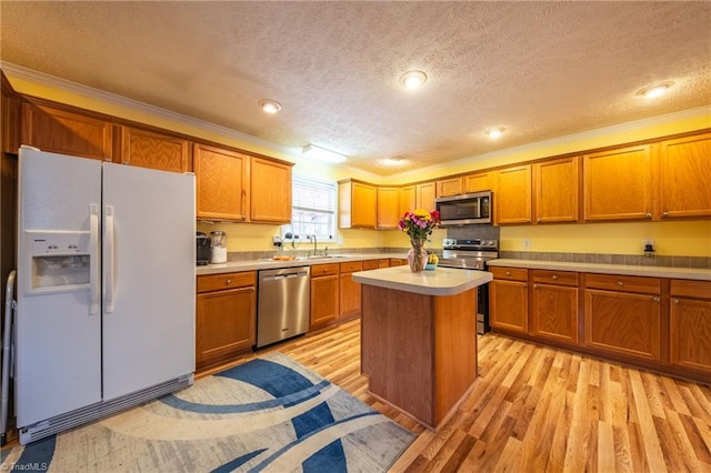 kitchen with sink, stainless steel appliances, a center island, light hardwood / wood-style floors, and a textured ceiling