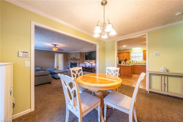 carpeted dining room with sink, ornamental molding, a chandelier, and a textured ceiling