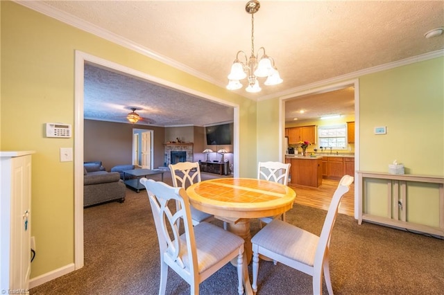 carpeted dining room with sink, crown molding, a chandelier, and a textured ceiling