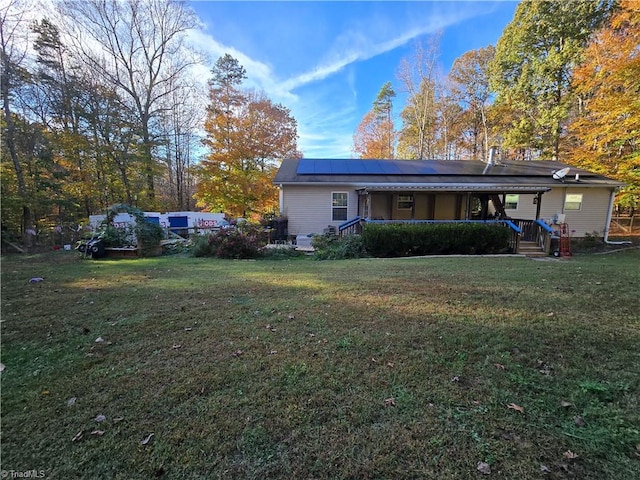 back of house with a porch, a yard, and solar panels