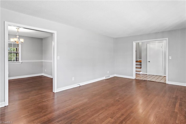 unfurnished room featuring an inviting chandelier and dark hardwood / wood-style flooring