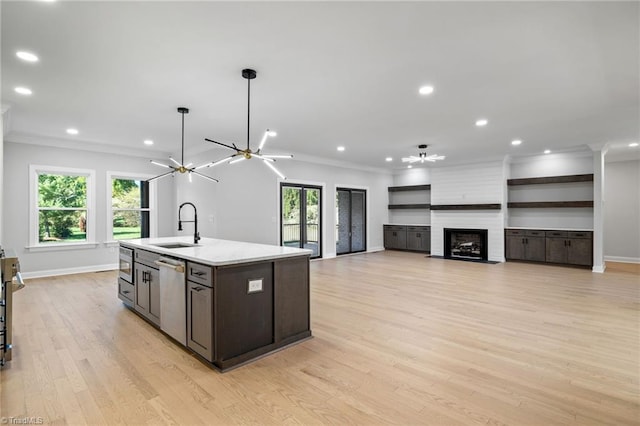 kitchen with a sink, a kitchen island with sink, a healthy amount of sunlight, appliances with stainless steel finishes, and ornamental molding