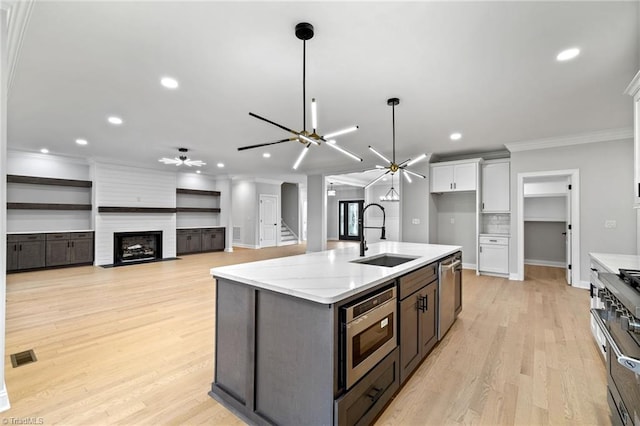 kitchen with a ceiling fan, ornamental molding, a sink, appliances with stainless steel finishes, and white cabinetry