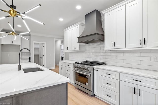 kitchen featuring a sink, tasteful backsplash, custom exhaust hood, crown molding, and high end range