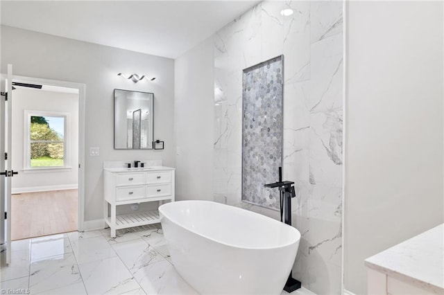bathroom featuring baseboards, a soaking tub, marble finish floor, and vanity
