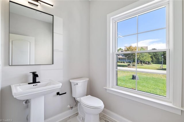 bathroom with a wealth of natural light, toilet, and baseboards