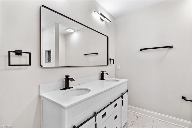 bathroom with baseboards, marble finish floor, a sink, and double vanity