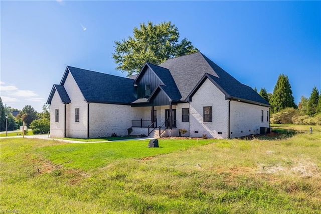 view of front of house with brick siding, a shingled roof, board and batten siding, crawl space, and a front yard