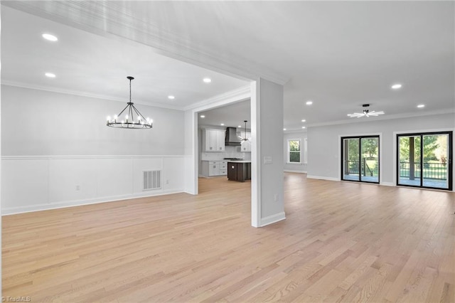 unfurnished living room featuring an inviting chandelier, ornamental molding, visible vents, and light wood-type flooring