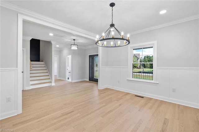 empty room featuring stairway, an inviting chandelier, light wood-style flooring, ornamental molding, and visible vents