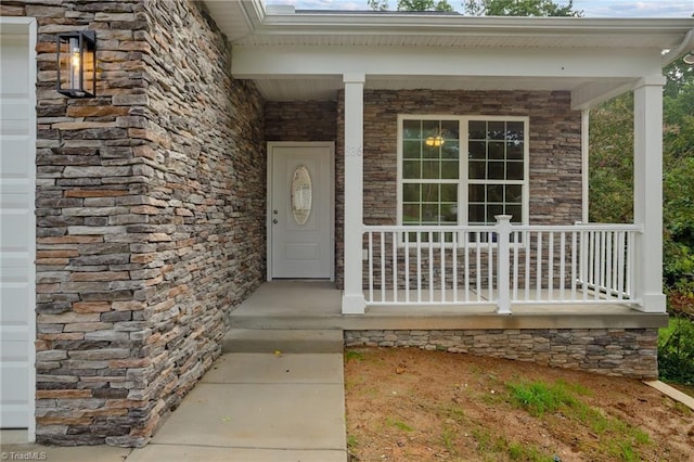 doorway to property featuring stone siding and a porch