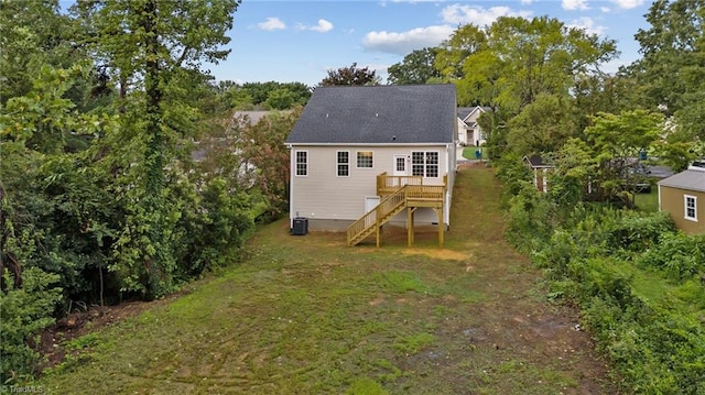 rear view of property featuring a deck, a yard, and central AC