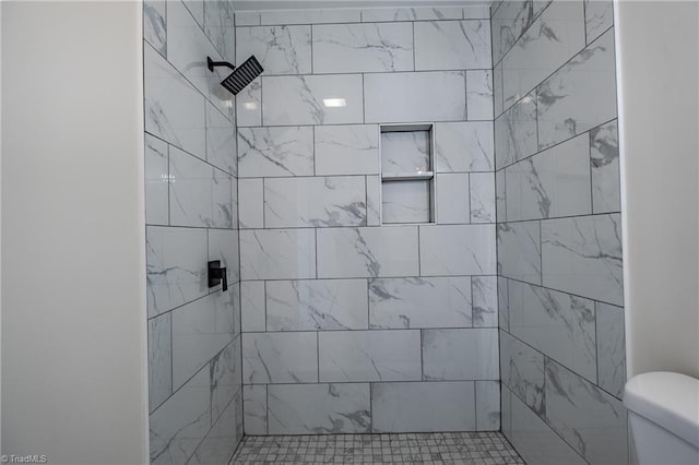 bathroom with a tile shower and toilet