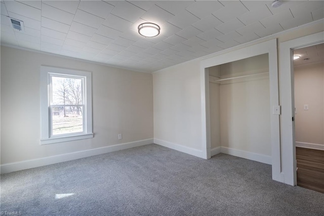 unfurnished bedroom with ornamental molding, a closet, and dark colored carpet