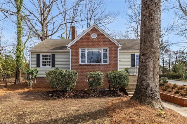 view of front of house featuring fence, brick siding, and a chimney