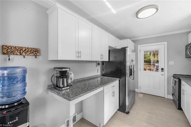 kitchen featuring visible vents, ornamental molding, dark stone countertops, stainless steel appliances, and white cabinets