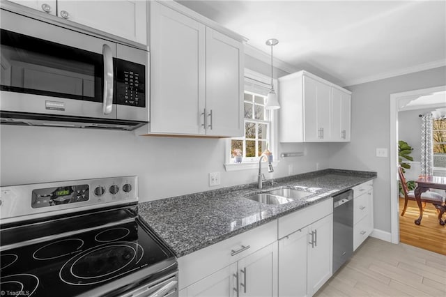 kitchen featuring white cabinets, stainless steel appliances, crown molding, and a sink