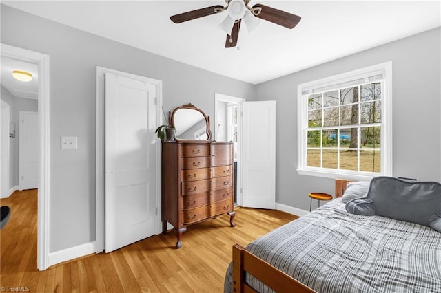 bedroom with light wood-style flooring, a ceiling fan, and baseboards