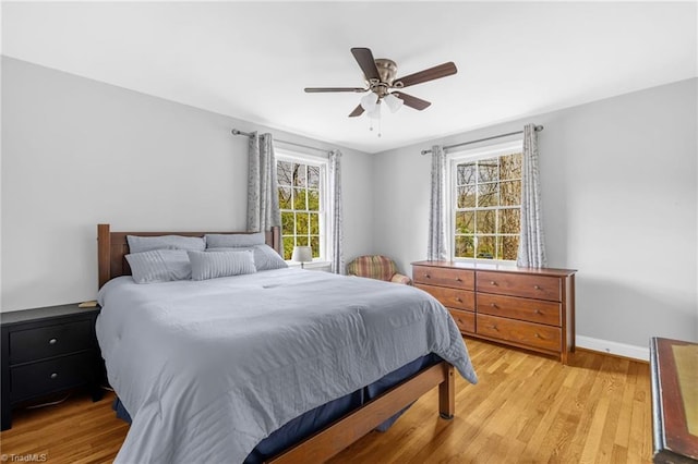 bedroom with a ceiling fan, baseboards, and light wood-type flooring