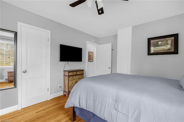 bedroom with a ceiling fan, baseboards, and wood finished floors