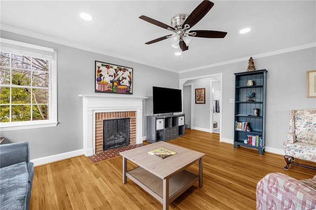 living area with baseboards, recessed lighting, light wood-style floors, crown molding, and a brick fireplace