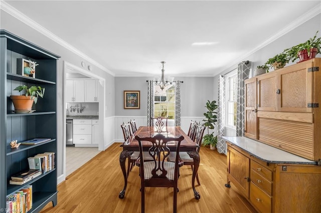 dining space with wainscoting, light wood-style flooring, built in shelves, and ornamental molding