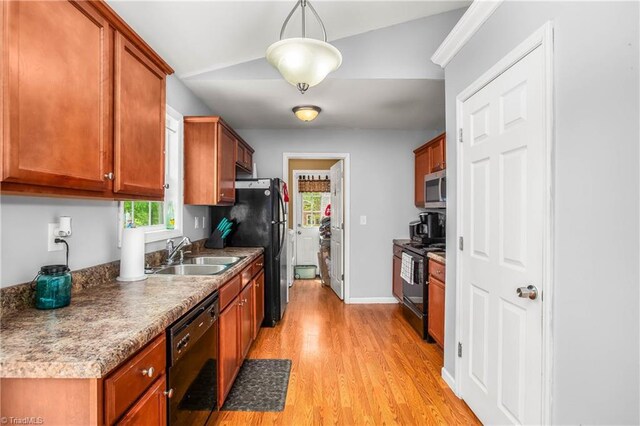 kitchen with black appliances, light wood finished floors, a sink, and brown cabinetry