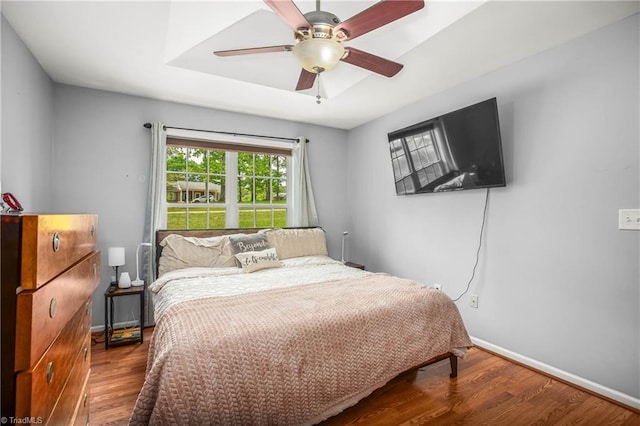 bedroom with ceiling fan, wood finished floors, and baseboards